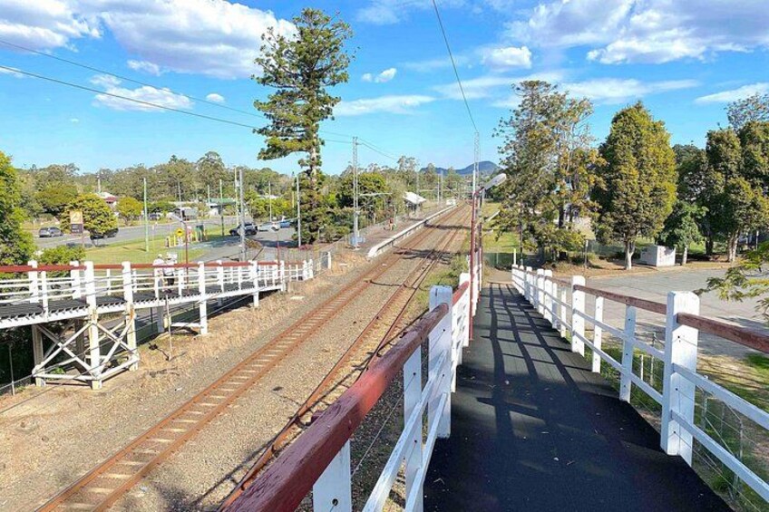 A railway bridge with white railings, tracks, and a clear sky. 3