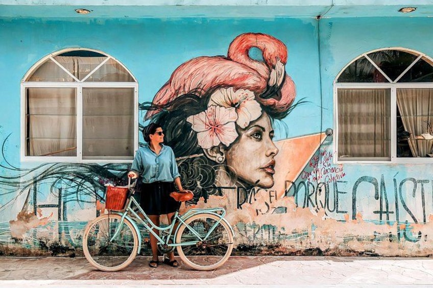 A mural with a woman's portrait, a bicycle, and a building facade. 5