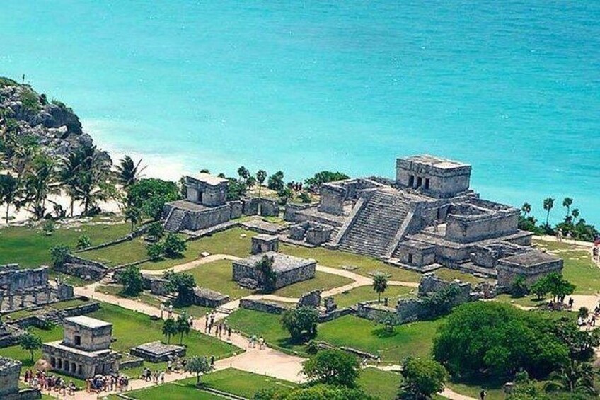 An ancient Mayan city with large stone structures near a beach. 1