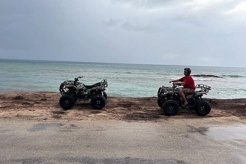 Two ATVs parked on a beach with the ocean in the background. 4