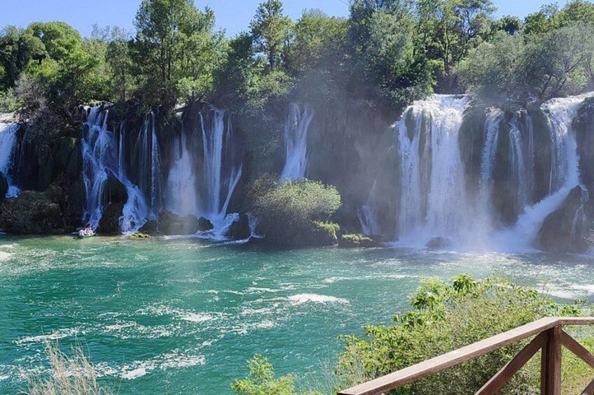 A waterfall cascading over rocks into a turquoise river surrounded by greenery. 5