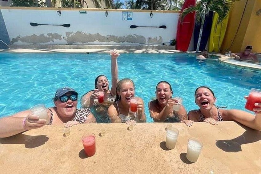 Un groupe de personnes se trouve dans une piscine, avec des boissons posées sur le bord. 3