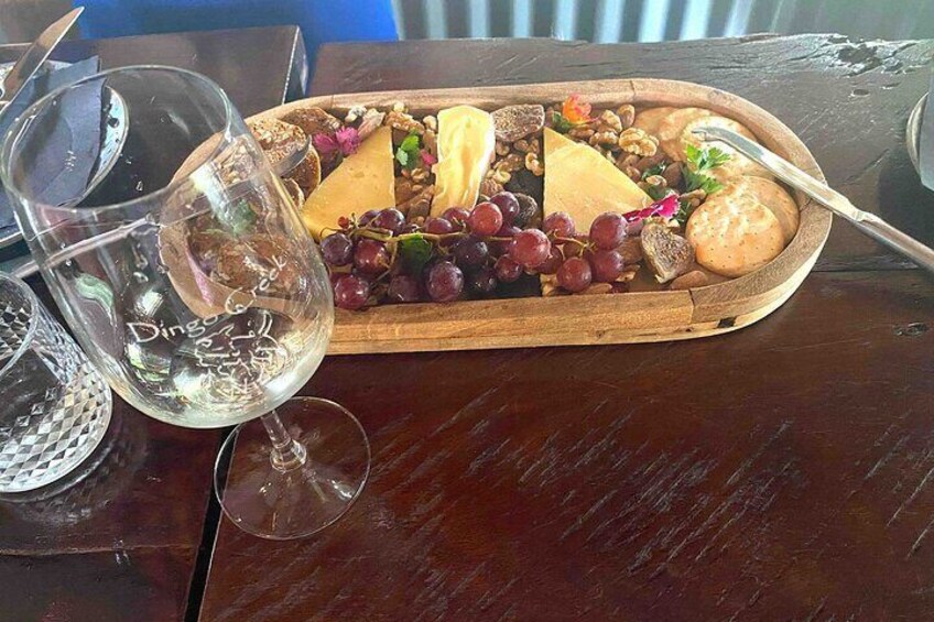 A charcuterie board with cheese, grapes, nuts, and crackers on a wooden tray. 5