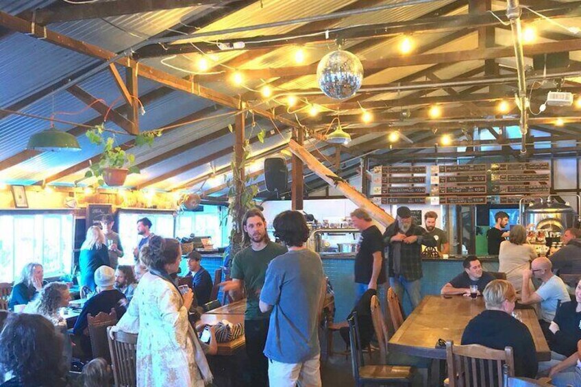 A bustling indoor dining area with wooden tables and chairs, hanging lights, and a bar counter. 4