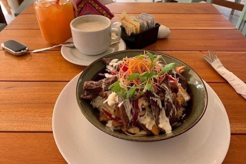 Una comida con un plato de alimentos, una taza de café y un vaso de jugo de naranja sobre una mesa de madera. 2