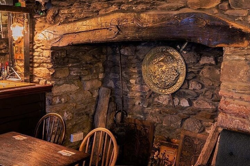 A stone fireplace with a decorative plate, wooden chairs, and a rustic interior. 3