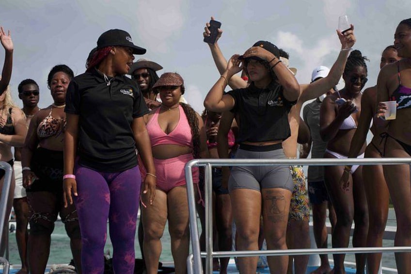 Un grupo de personas en un bote, algunas con traje de baño, y una barandilla al frente. 5
