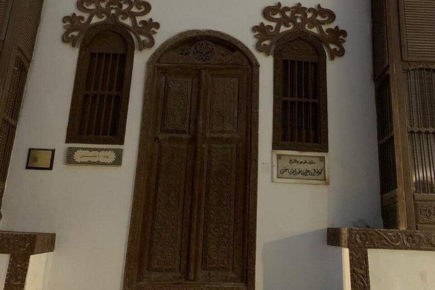Un edificio con una puerta de madera grande y dos ventanas arqueadas con detalles decorativos. 4