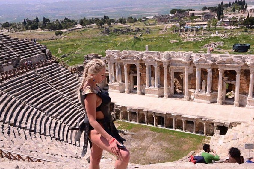 An ancient amphitheater with stone seating and columns, overlooking a hilly landscape with ruins. 2