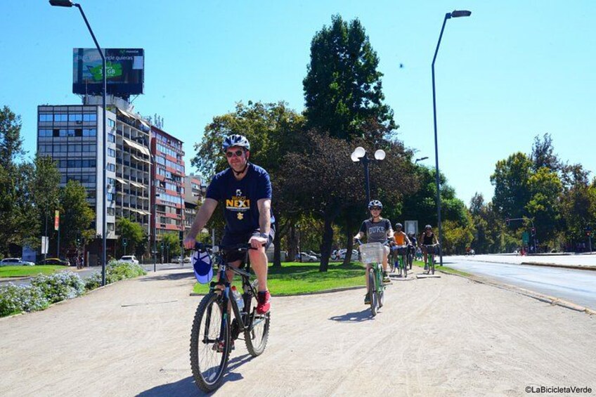 Ein Radfahrer auf einem asphaltierten Weg, im Hintergrund Bäume und ein Gebäude. 5