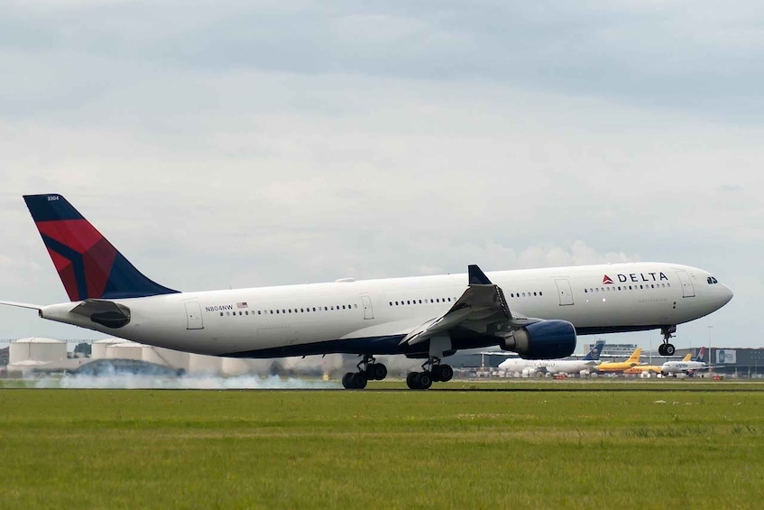 Un avión Delta en la pista con humo de fondo. 3
