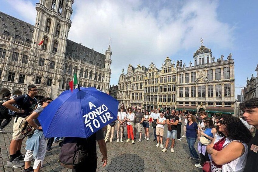 A crowd in front of a historic building with a blue umbrella labeled 'A ZONZO TOUR'. 3