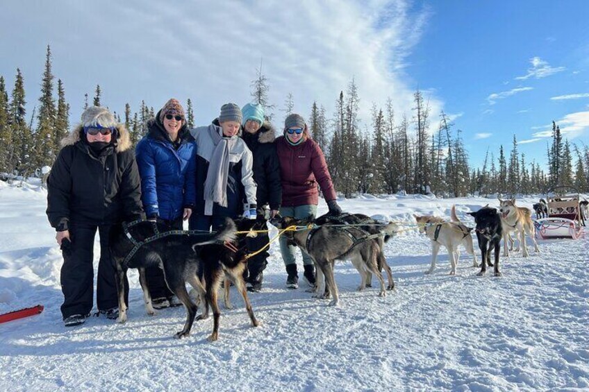 A group of people with sled dogs on a snowy trail. 1