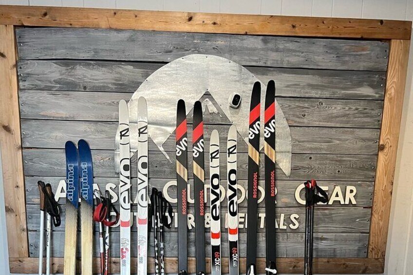 A collection of skis and snowboards on a wooden wall. 4