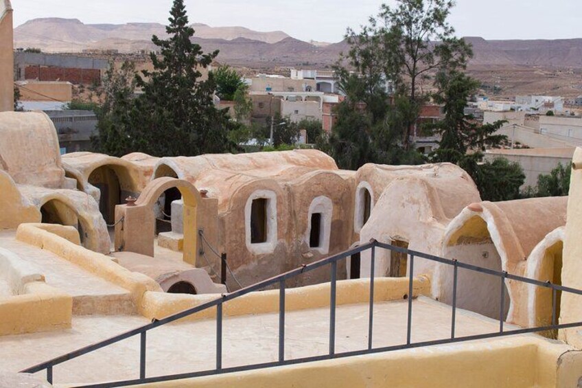 A terraced structure with arches, a metal railing, and a mountainous backdrop. 5