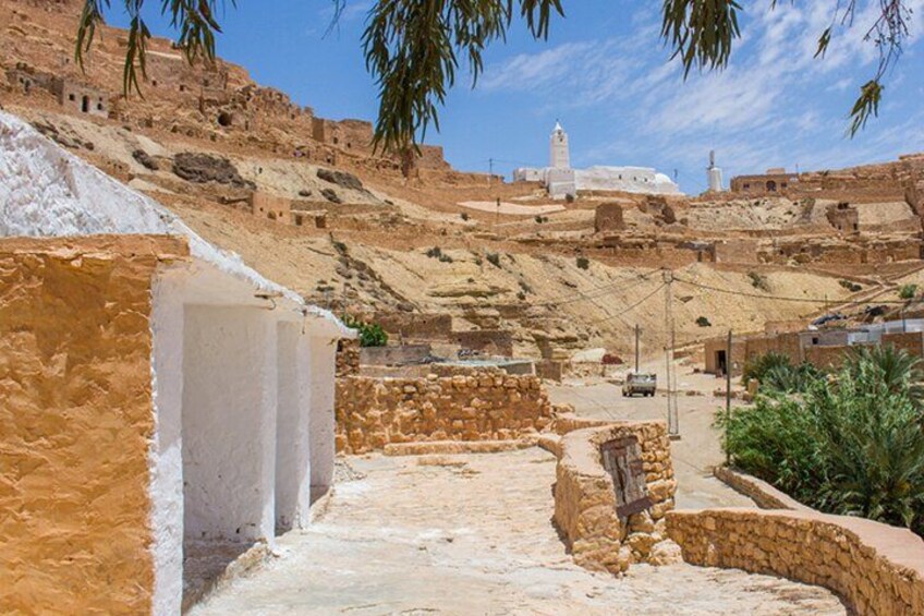 A desert landscape with ancient ruins, a white minaret, and a clear sky. 3