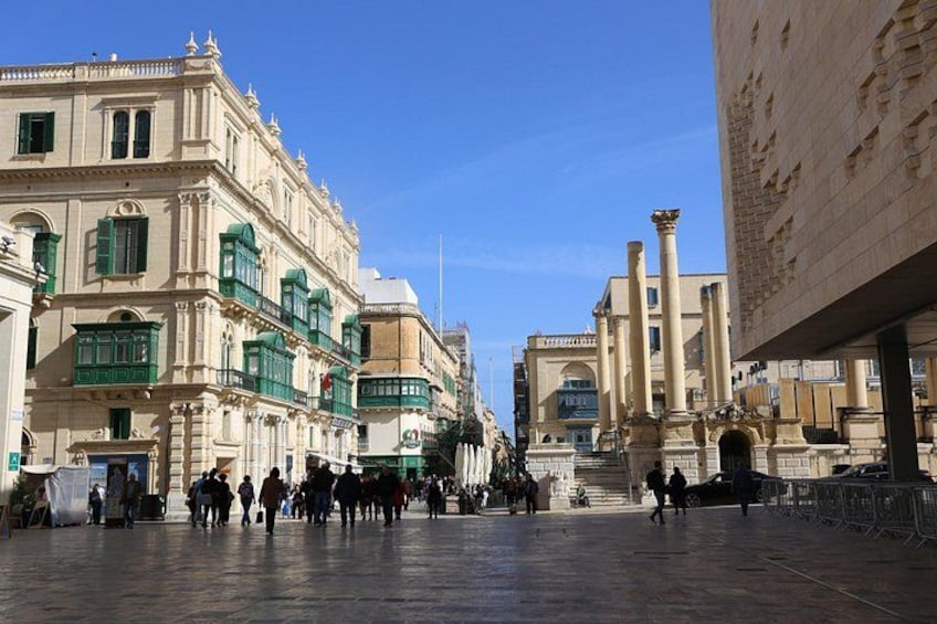A historic square with classical architecture, including columns and ornate buildings. 1