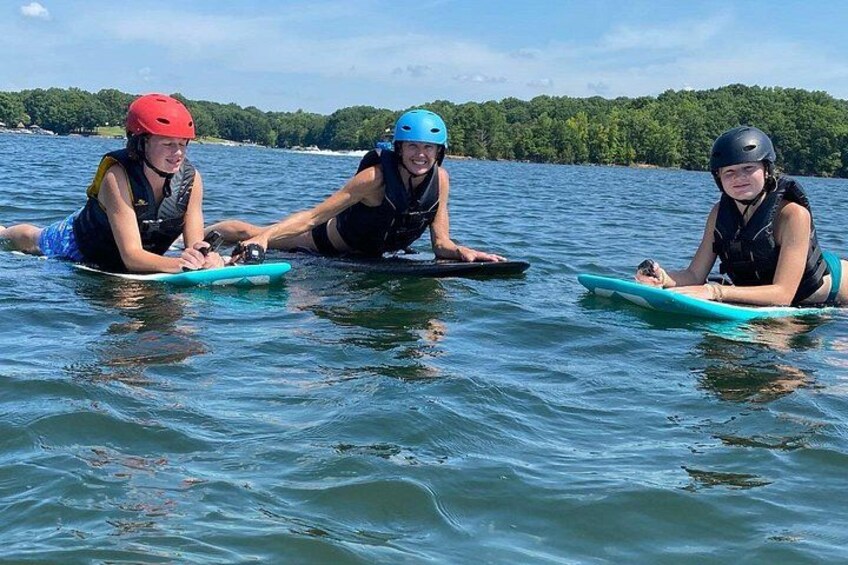 Three people on a calm lake with kayaks, wearing helmets and life vests. 5