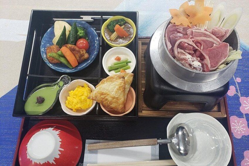 A meal tray with various dishes including vegetables, meat, and a hot pot. 2