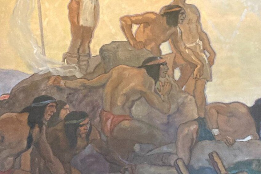 Eine Gruppe von Menschen in einer Höhle, einige stehen, andere sitzen, im Hintergrund weht eine Flagge. 3