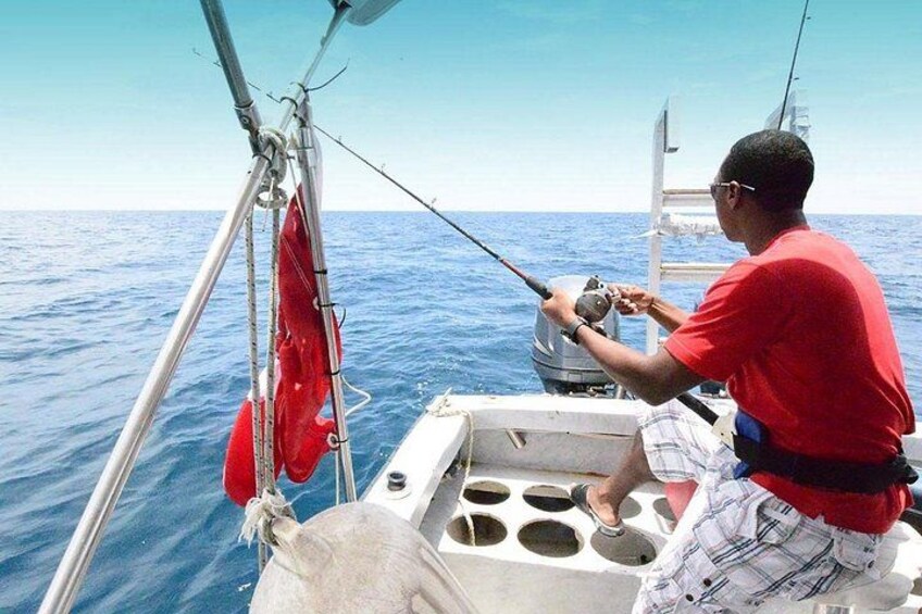 Une personne pêchant sur un bateau, sous un ciel bleu dégagé et sur une mer calme. 2
