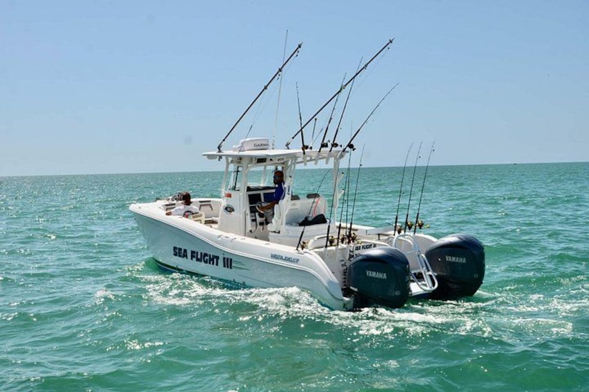 Un bateau blanc nommé « SEA FLIGHT III », équipé de deux moteurs hors-bord Yamaha, navigue sur une eau turquoise. 4