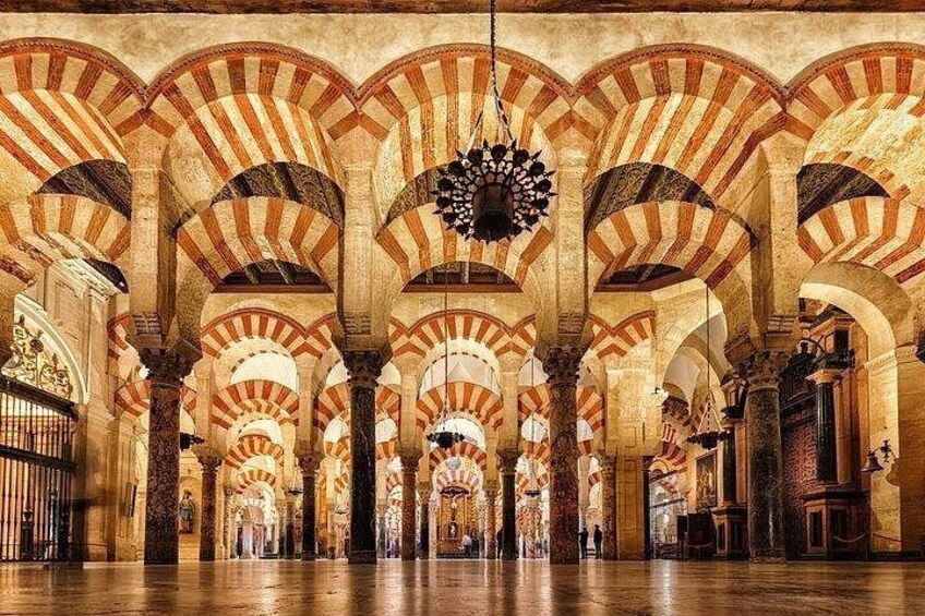 Innenansicht einer Moschee mit gestreiften Bögen und einem Chandelier. 2