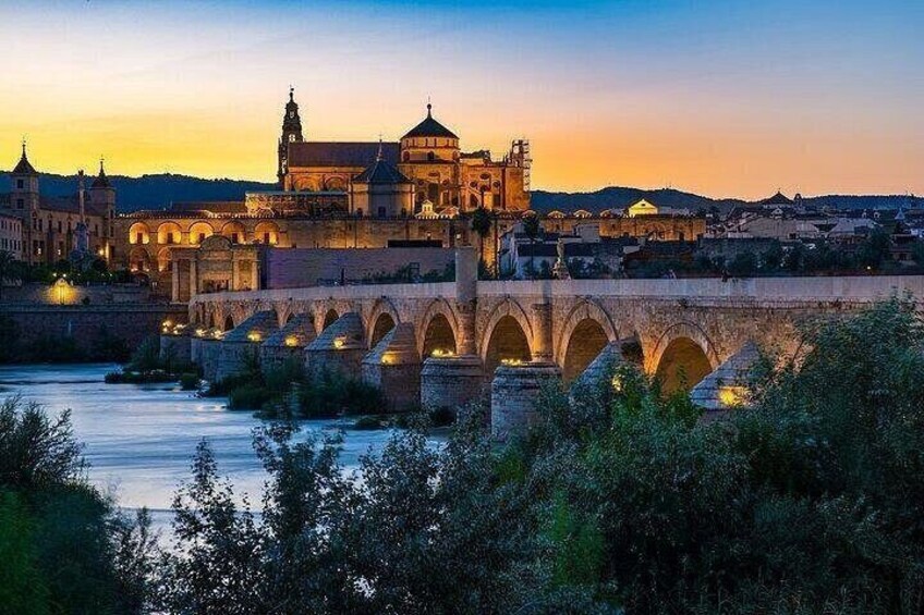 Eine historische Brücke mit Bögen, ein Fluss und ein schlösserähnliches Gebäude im Hintergrund. 3