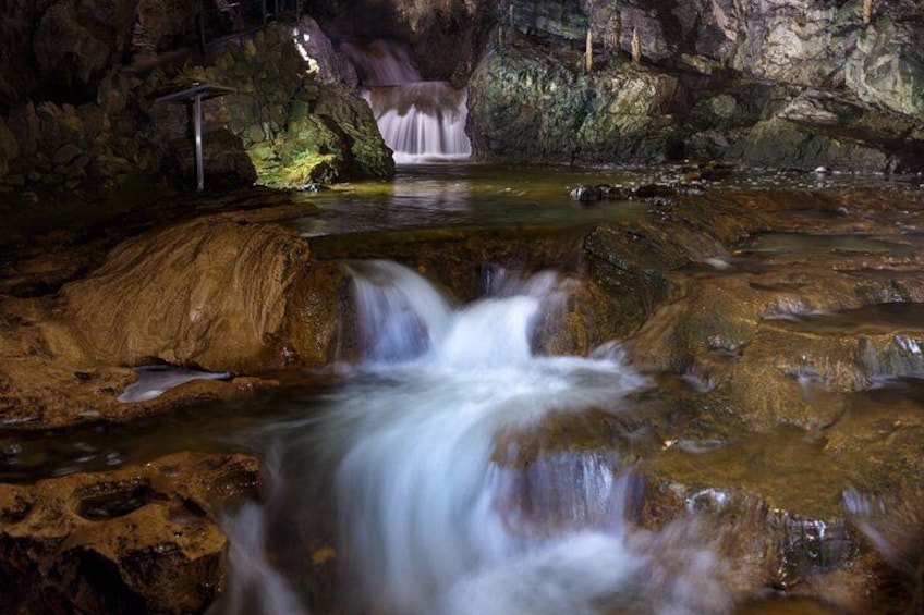 A cave waterfall with a stream flowing over rocks. 3