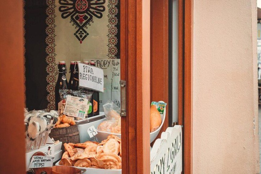 A cluttered shop entrance with various items like bottles, bread, and a sign reading 'PIPA REGIONAL.' 2