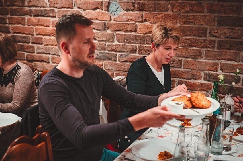 En person som serverar mat vid ett bord med en tegelvägg i bakgrunden. 4
