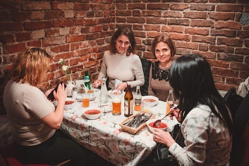En grupp människor som äter vid ett bord med en tegelvägg i bakgrunden. 5