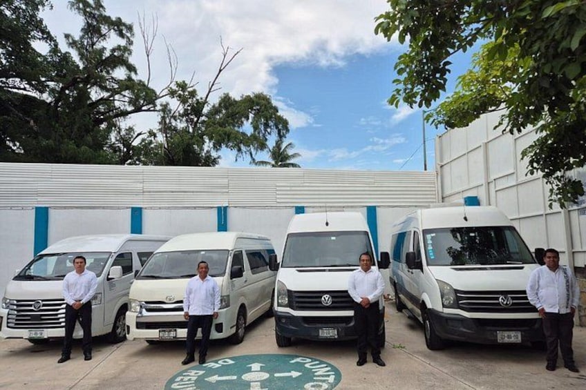 Four white vans parked in front of a building with a blue and white color scheme. 3