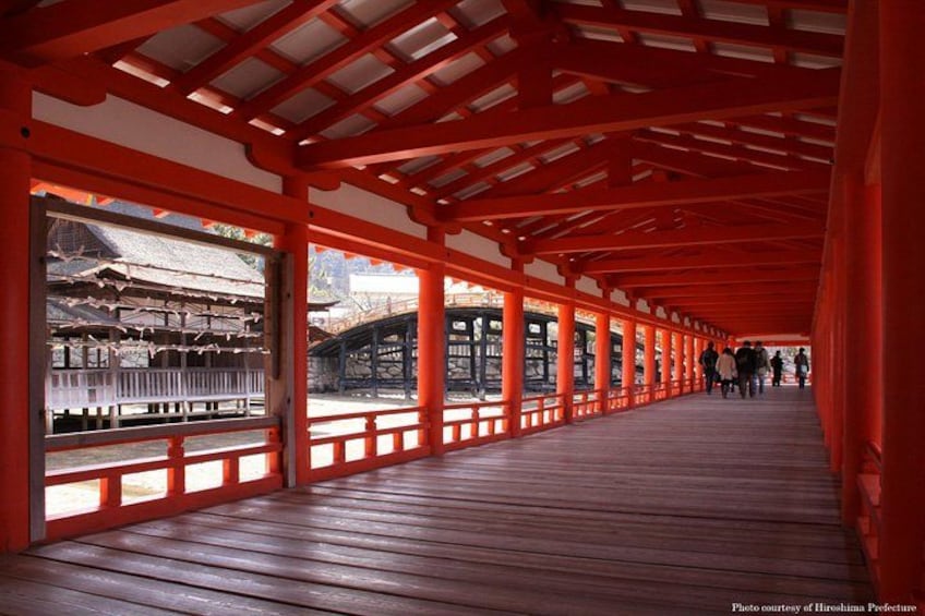 A wooden walkway with red pillars and a traditional Japanese building in the background. 3