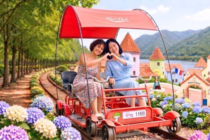 Una pareja en un carrete rojo por un sendero pintoresco con casas y flores coloridas. 1