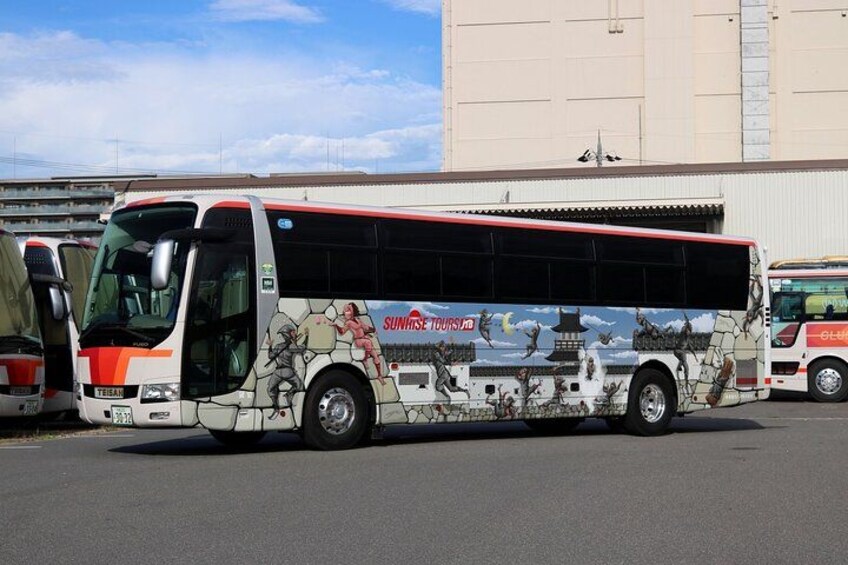 A tour bus with a mural of a dragon and traditional architecture. 2