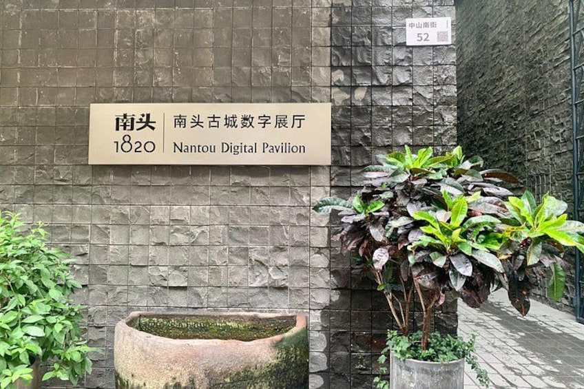 A stone wall with a sign for Nantou Digital Pavilion, a potted plant, and a stone planter. 5