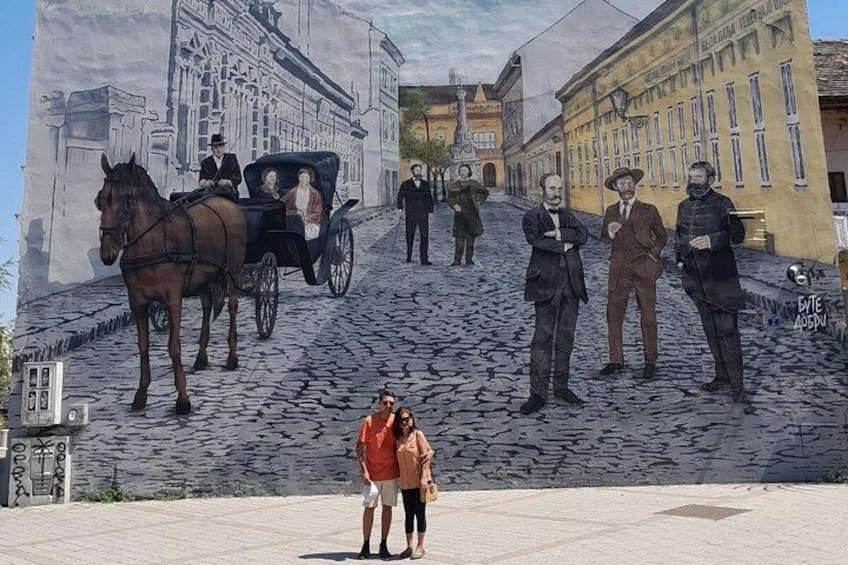 A mural of a horse-drawn carriage on a cobblestone street with buildings in the background. 5