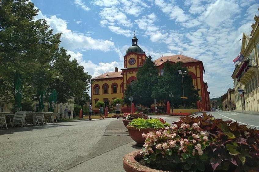 A church with a clock tower, surrounded by trees and flower beds. 2