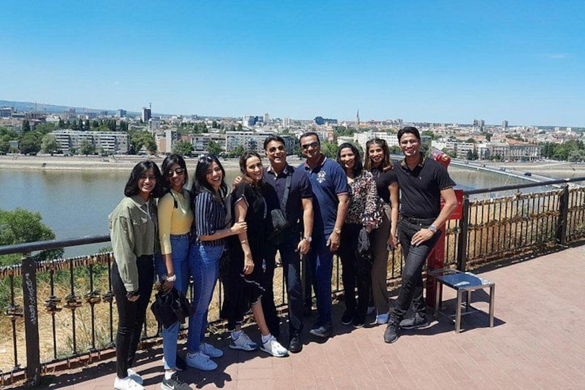 A group of people standing on a bridge with a river and cityscape in the background. 1