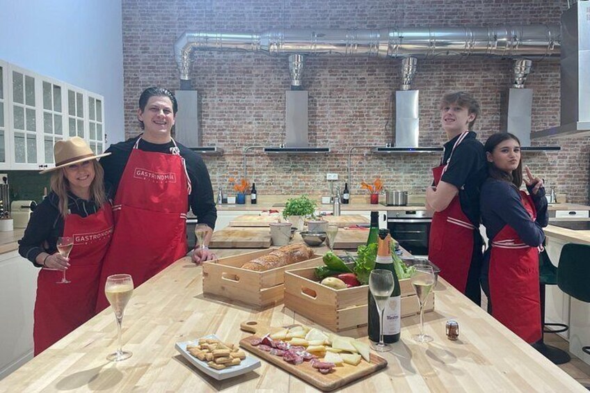 Une cuisine aux murs de briques, avec un comptoir en bois et des personnes portant des tabliers rouges. 1