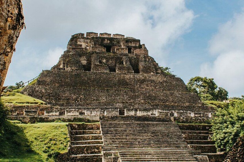 Une grande pyramide antique, avec un escalier menant à son sommet, entourée de verdure. 5