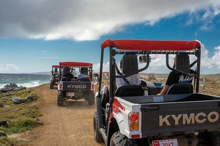 Off-road vehicles on a sandy path near the ocean. 2
