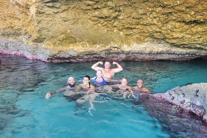 A group of people in a natural pool with clear water, surrounded by rocky cliffs. 2
