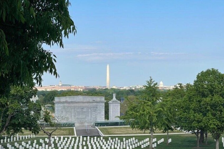 Een kerkhof met witte grafstenen, een monument en de Washington Monument op de achtergrond. 4