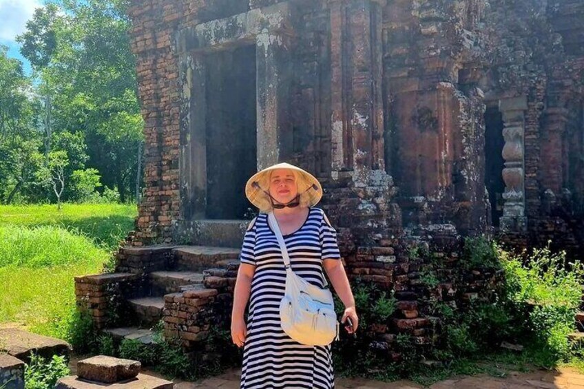 A person standing in front of an ancient brick structure with steps leading up to a doorway. 1