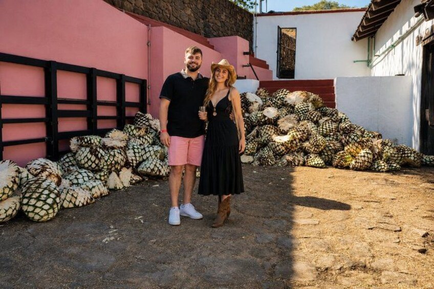 Deux personnes se tiennent devant une pile de noix de coco, avec un bâtiment rose et un bâtiment blanc en arrière-plan. 2