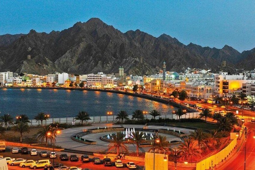 A coastal cityscape with a marina, a roundabout, and mountains in the background. 1