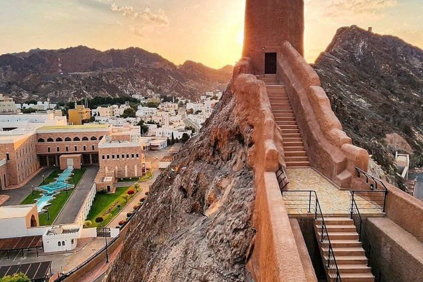A staircase leading up to a tower, a building with arches, and a mountainous landscape. 5