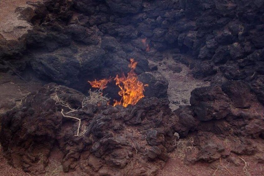 A fire burning on a rocky surface with dark, uneven terrain. 3
